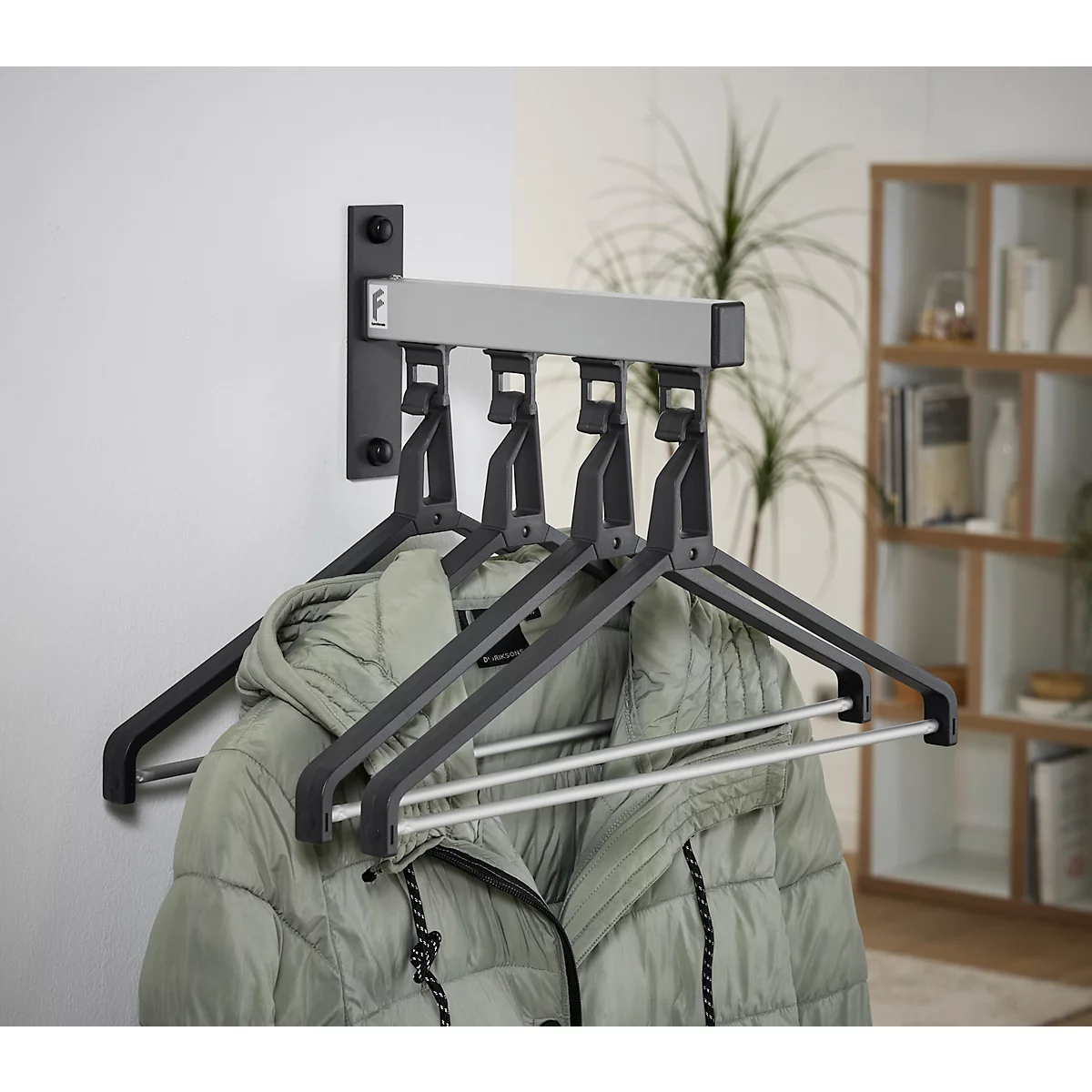 Wandgarderobe mit grauen Kleiderbügeln, an denen eine Jacke hängt. Im Hintergrund ist ein Regal zu sehen.