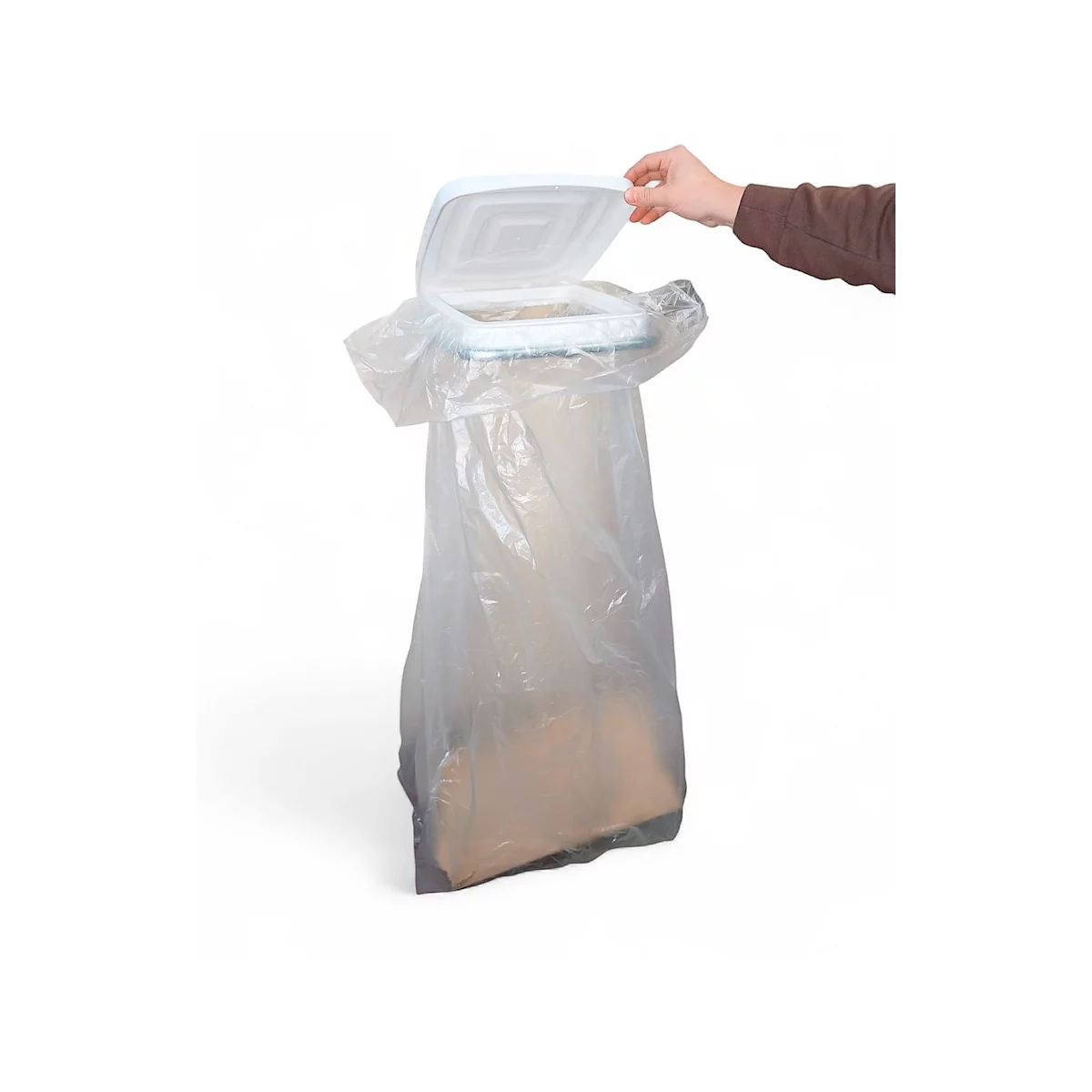 Een hand opent het deksel van een witte vuilnisbak met een doorzichtige plastic zak.