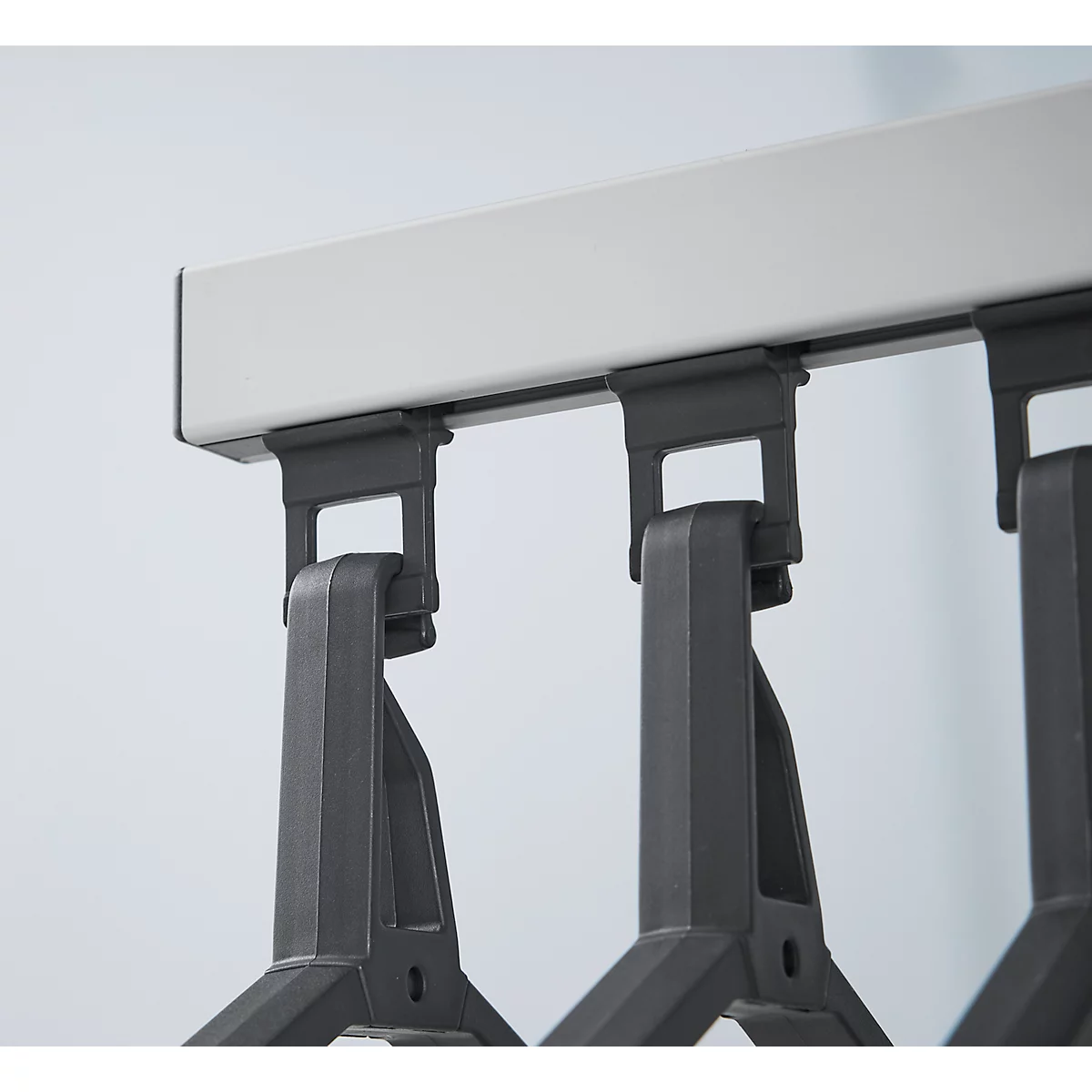 Close-up van een grijze kledingrail met hangende kleerhangers.