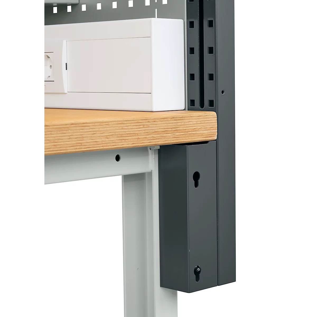 Nahaufnahme einer Werkbank mit einer Holzplatte, einer weißen Box und einem grauen Metallrahmen. An der Seite sind Schlüsselform-Ausschnitte.