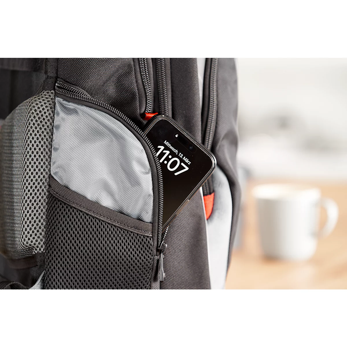 Smartphone dans la poche d'un sac à dos. L'heure 11:07 est visible sur l'écran.