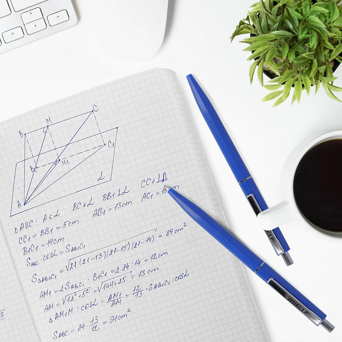 Draufsicht auf einen Schreibtisch mit Notizblock, Stiften, Kaffee und einer Pflanze. Auf dem Notizblock ist eine Geometrieaufgabe zu sehen.