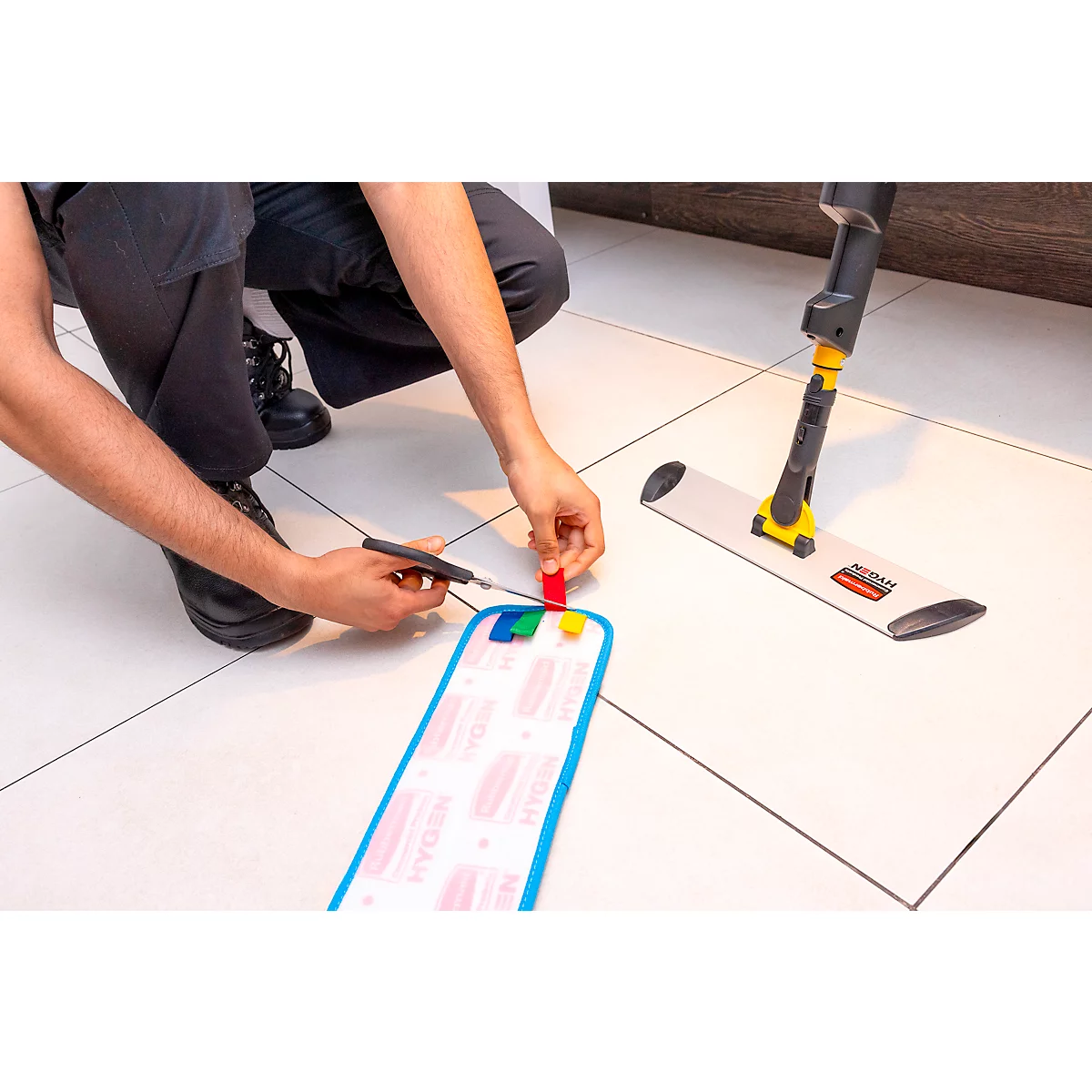 Person is assembling the mop on a tiled floor. The blue cleaning cloth is being inserted.