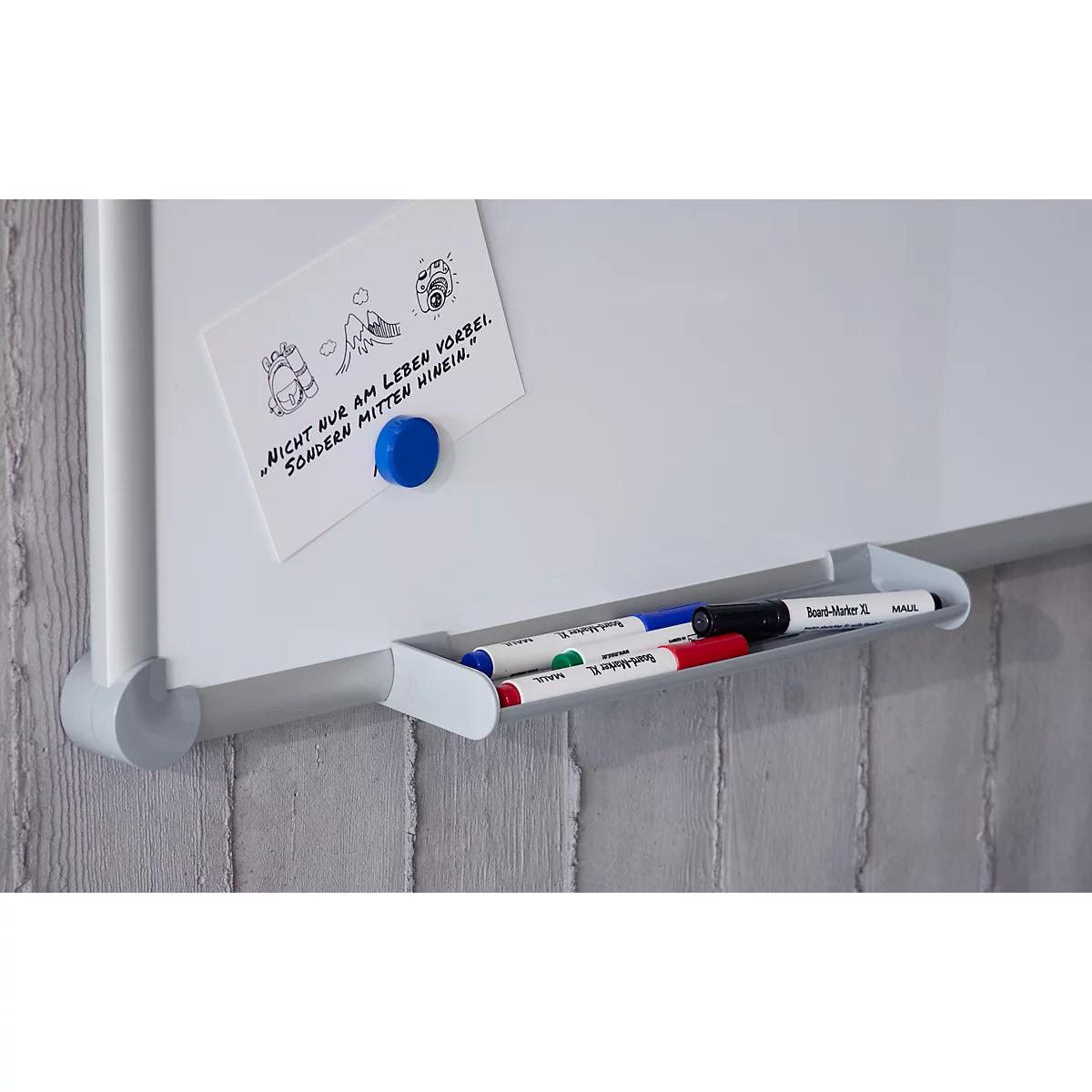 Weißes Whiteboard mit Ablage für Stifte und einer mit einem blauen Magneten befestigten Notiz.