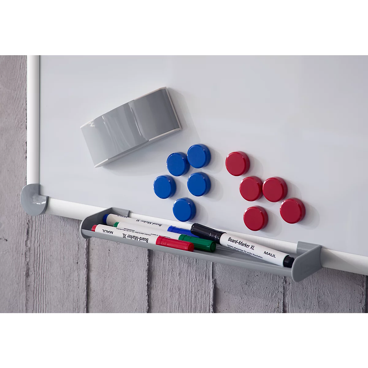 Weißes Whiteboard mit bunten Magneten und Stiften in einer Ablage.