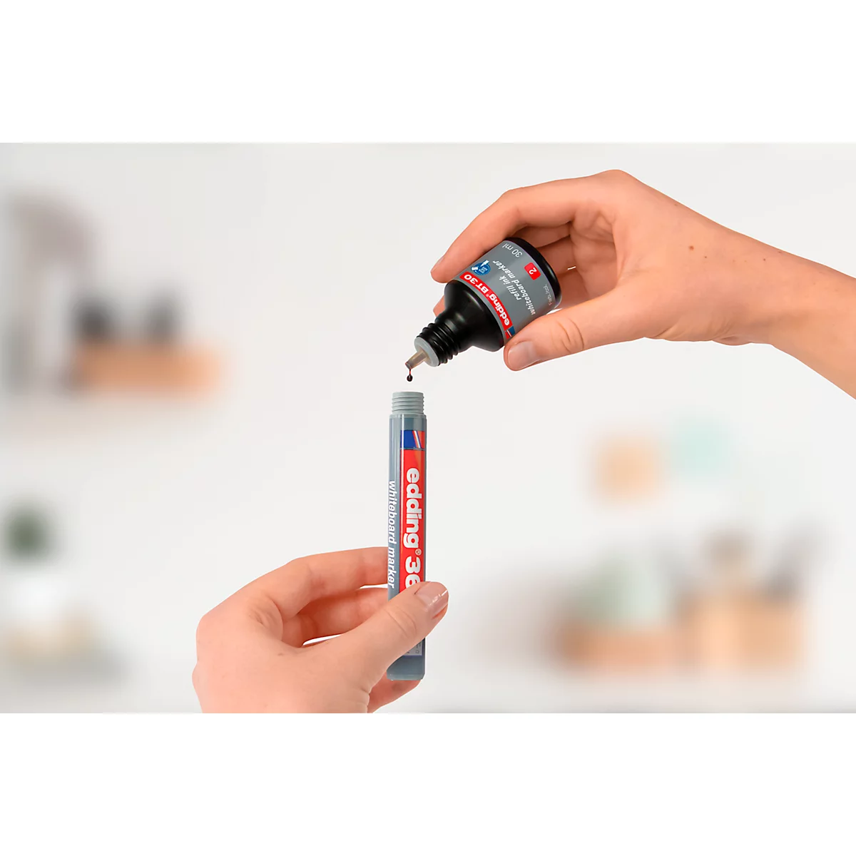 Hände füllen einen Edding 360 Marker mit Tinte aus einer Flasche. Tropfen fallen in den Marker.