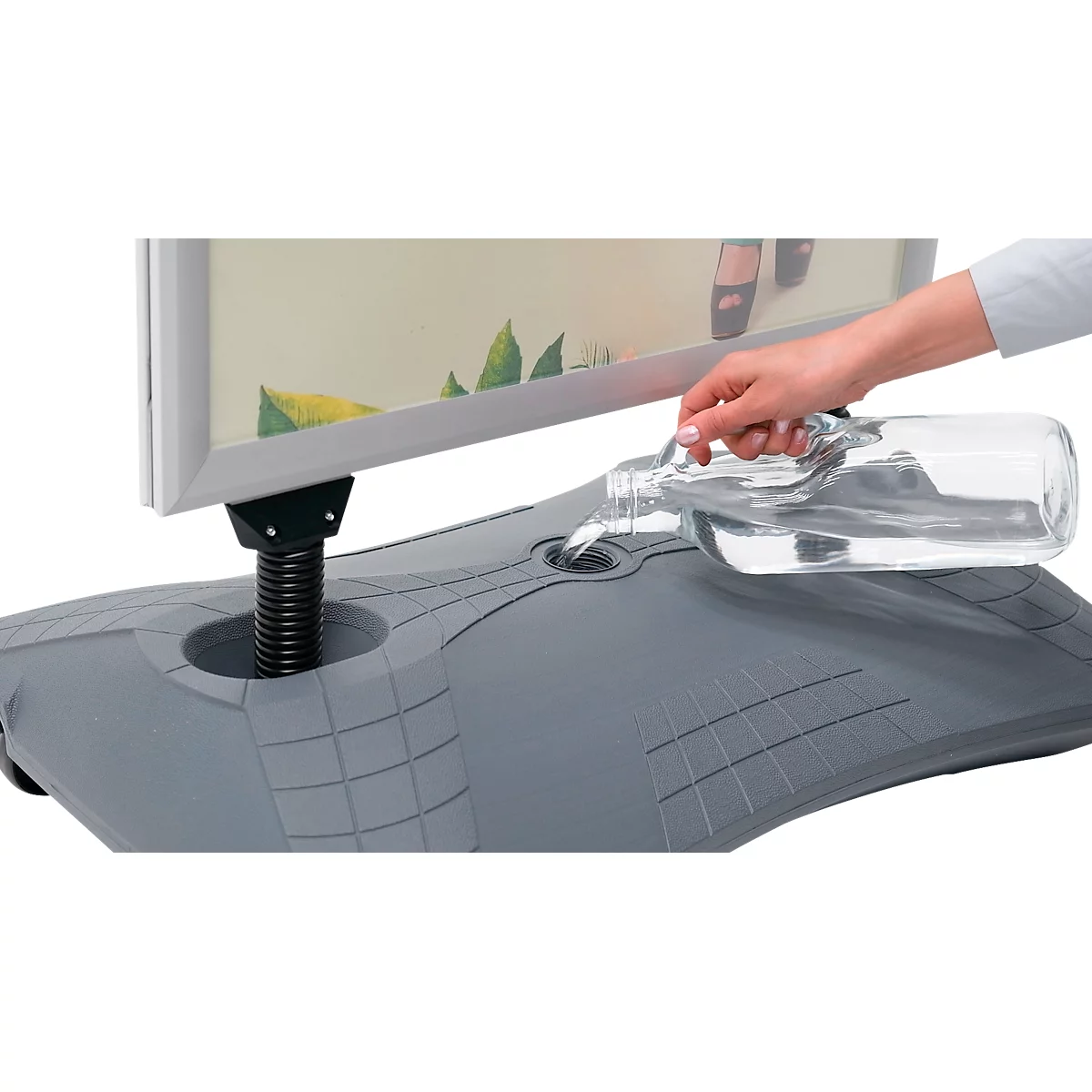 Een hand giet water in een standaard. De standaard houdt een reclamebord vast.