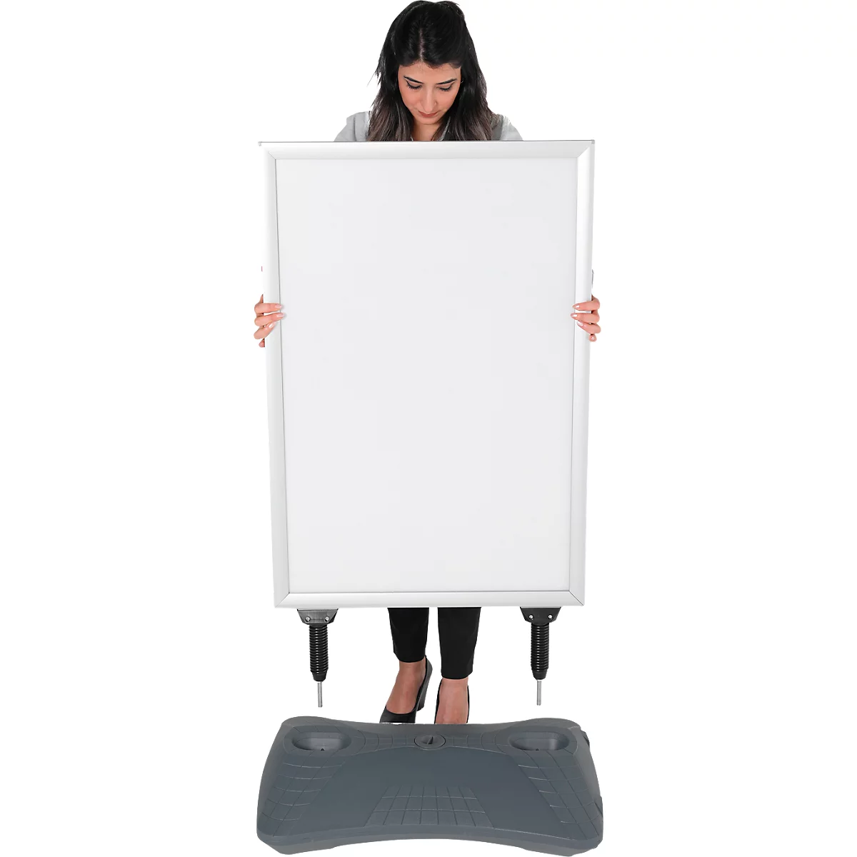 Une femme tient un grand tableau blanc vierge. Une base grise est au sol.