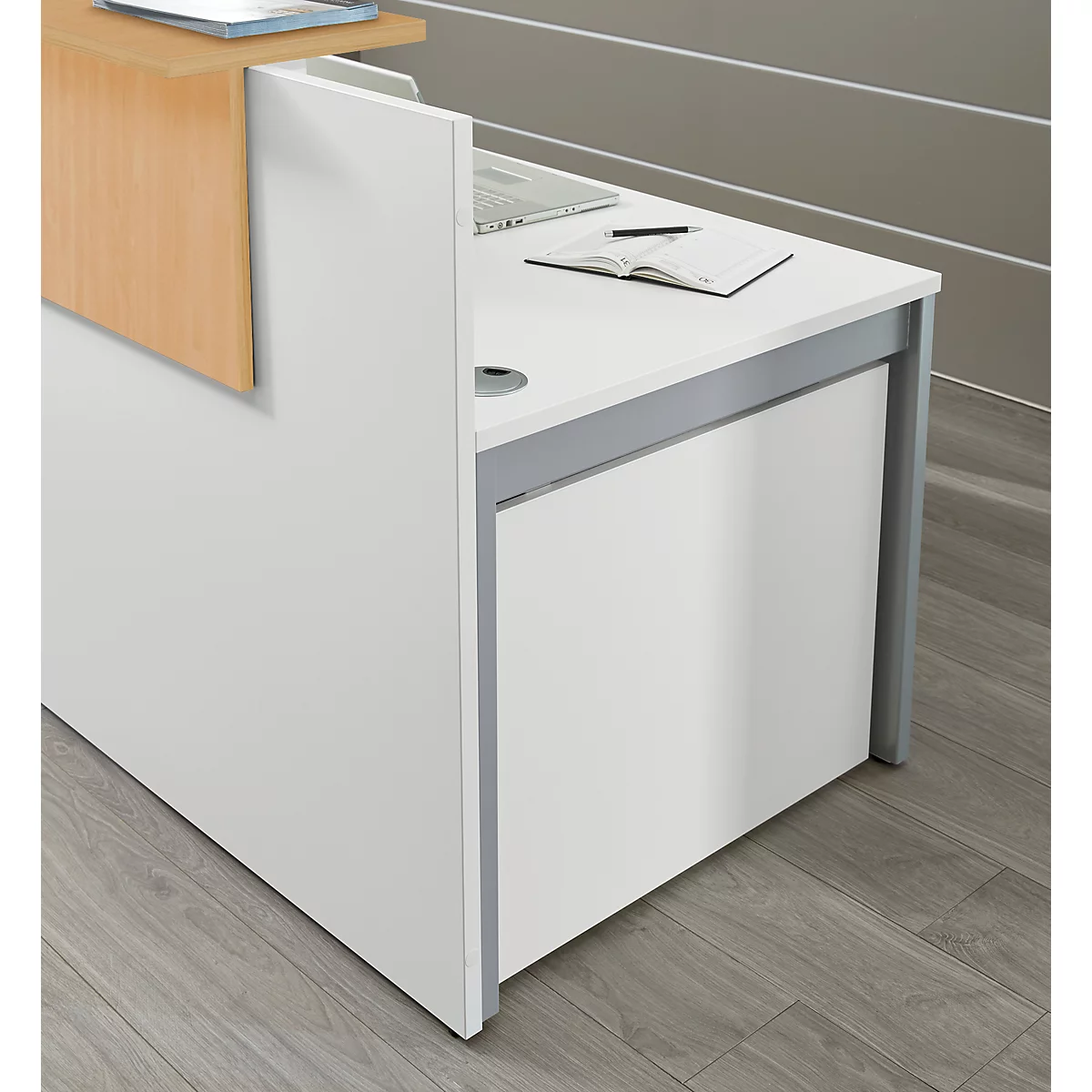 Büro-Empfangstheke in Weiss mit hellen Holzelementen und grauen Metallbeinen auf grauem Boden.