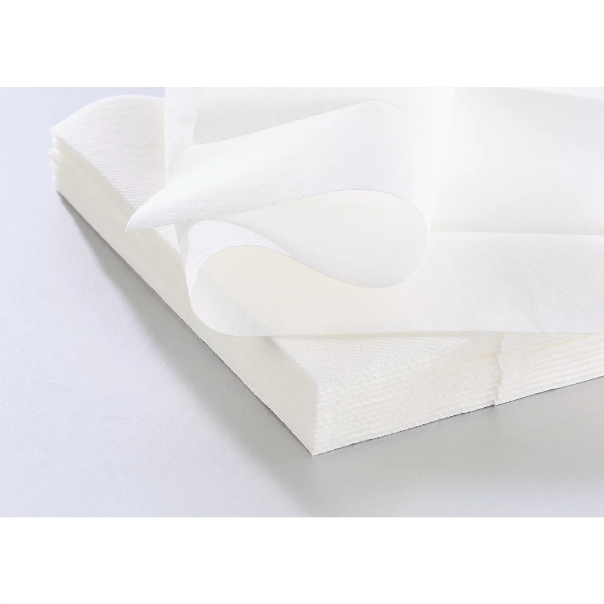 Een stapel witte papieren servetten, één vel omhooggevouwen.