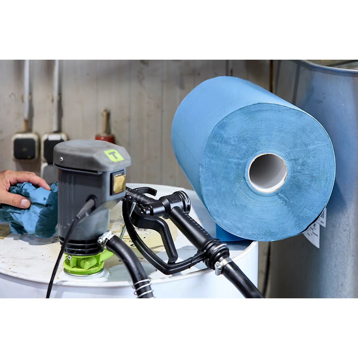 Eine elektrische Pumpe auf einem Fass neben einer blauen Papierrolle beim Reinigen.