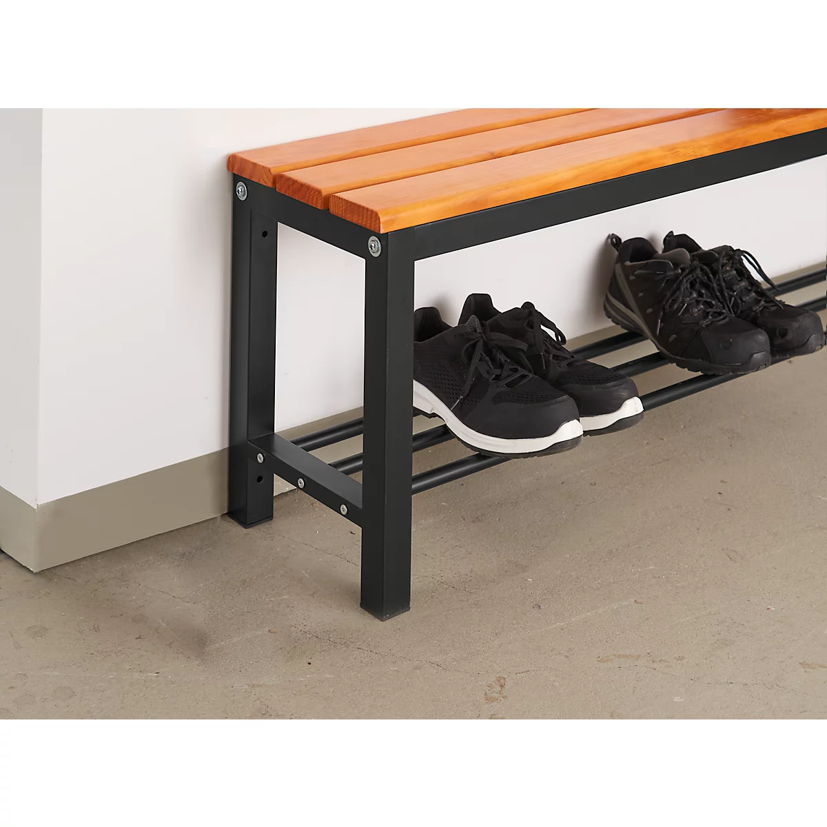A shoe bench with a wooden top and black metal frame. Black shoes are on the shelves.