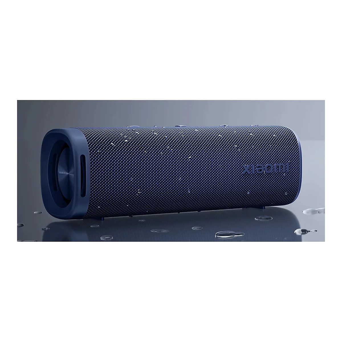 Blauer, zylinderförmiger Xiaomi-Lautsprecher auf einer glatten Fläche mit Wassertropfen.