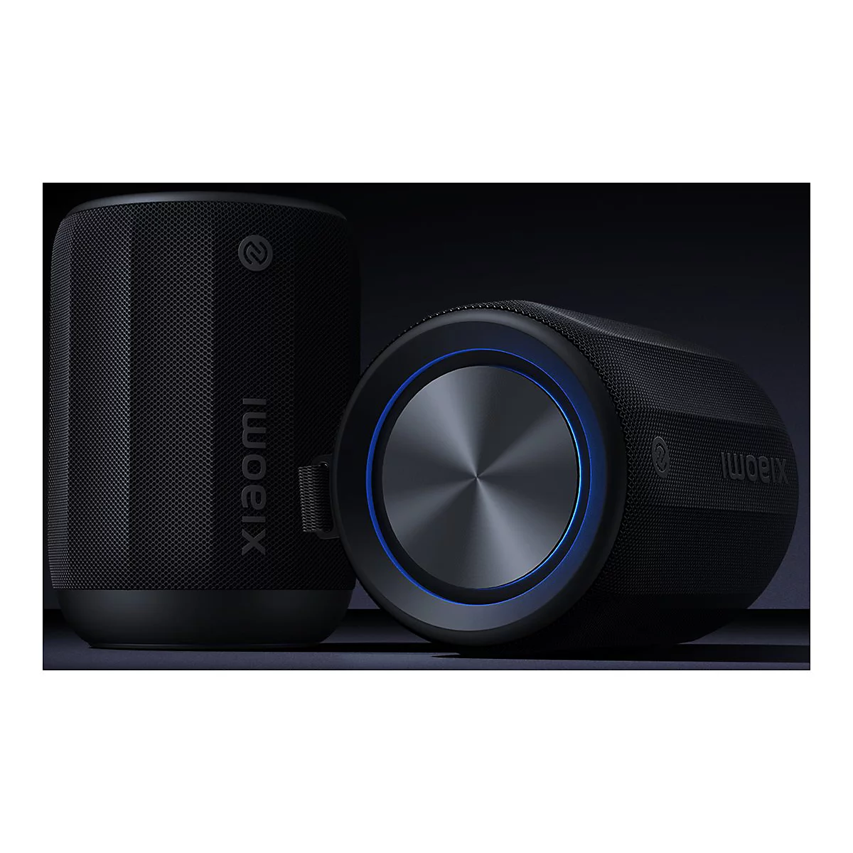 Zwei schwarze Xiaomi-Lautsprecher vor dunklem Hintergrund, einer stehend, einer liegend mit blau leuchtendem Ring.