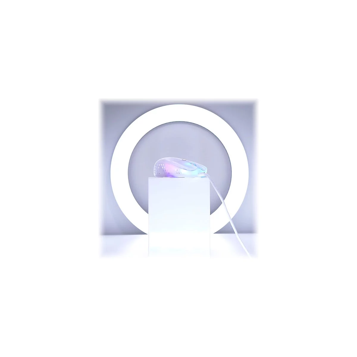 Weisse Gaming-Maus mit Regenbogen-RGB-Beleuchtung auf einem weissen Podest vor einem hellen Ring. Ein weisses Kabel ist angeschlossen.