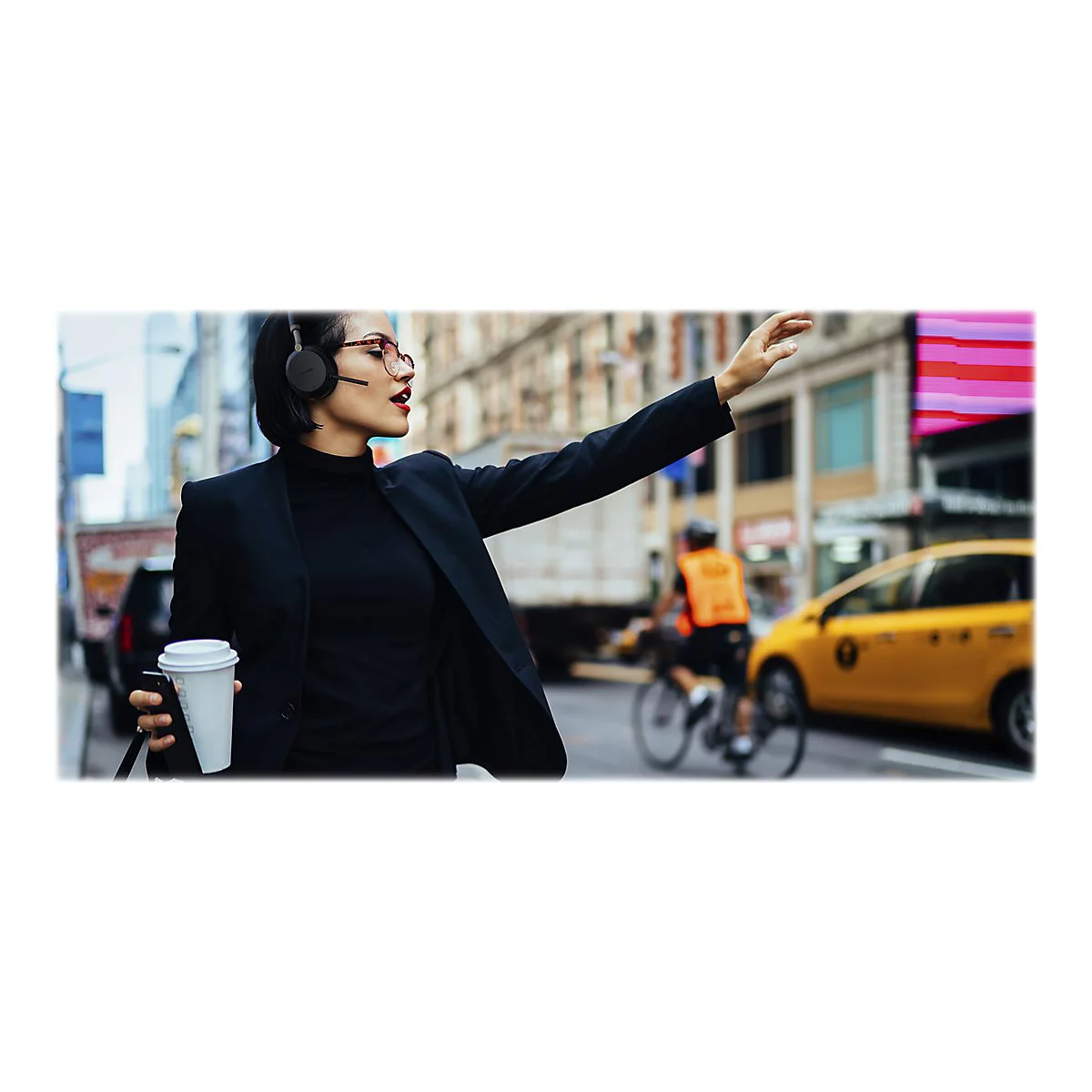 GeschÃ¤ftsfrau in New York winkt nach einem Taxi. Sie trÃ¤gt KopfhÃ¶rer und hÃ¤lt einen Kaffeebecher.