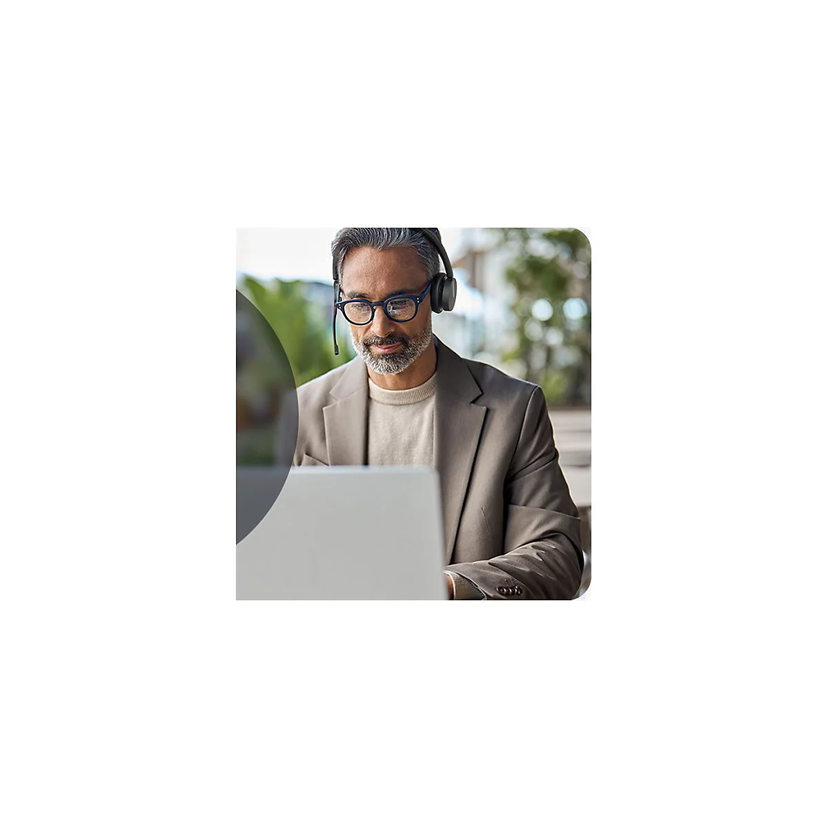 Ein Mann mit Brille und Headset sitzt am Laptop. Er trÃ¤gt ein Jackett.