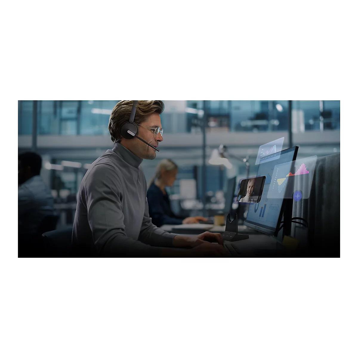 Ein Mann mit Headset arbeitet am Computer. Auf dem Bildschirm sieht man Videokonferenz und Diagramme.