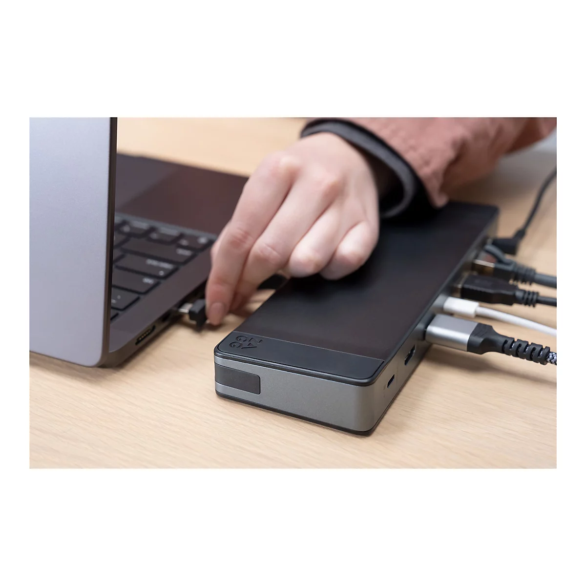 Main branchée à un hub USB connecté à un ordinateur portable. D'autres câbles sont branchés sur le hub.