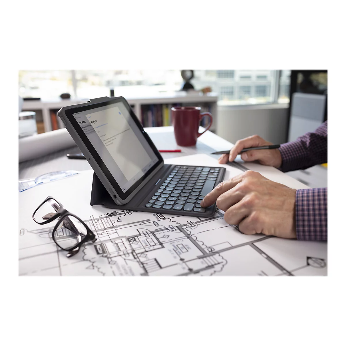 Person tippt auf Tablet-Tastatur, neben Brille und BauplÃ¤nen. Auf dem Tablet steht Notes.