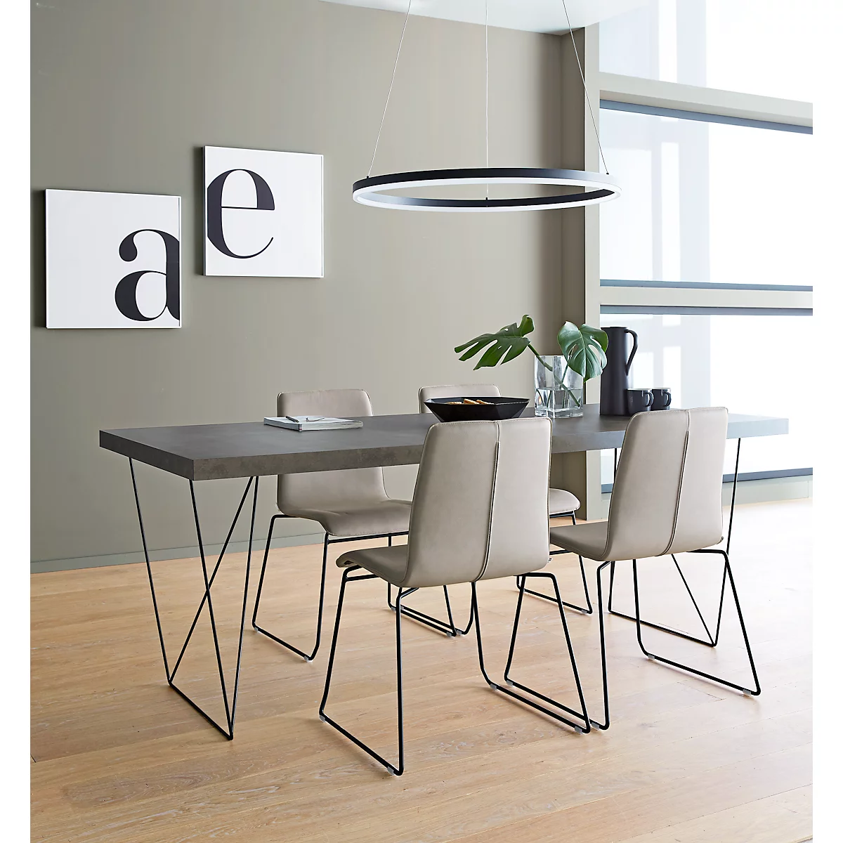 Dining room table with four chairs, pendant lamp. Two boards with the letters "a" and "e" are on the wall.