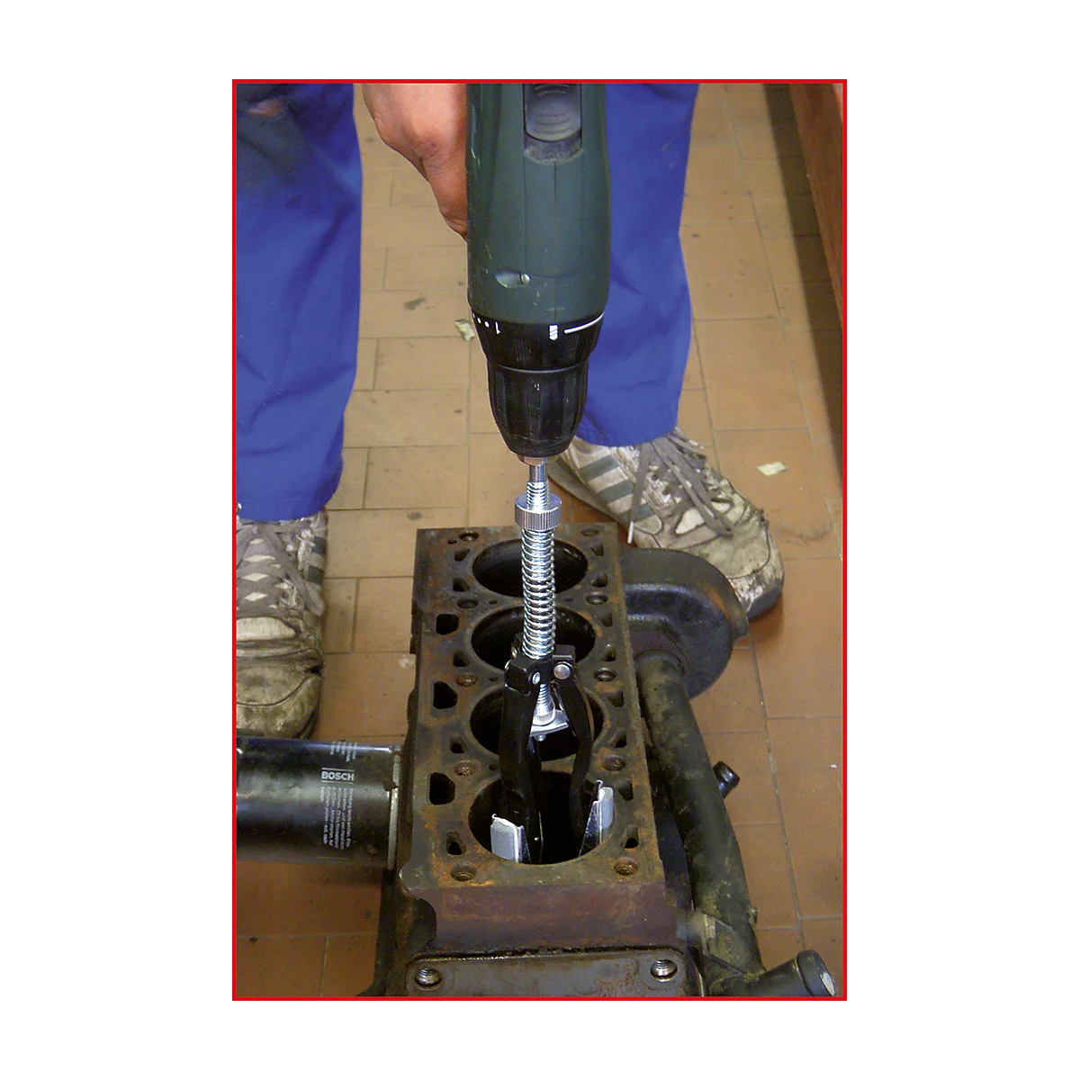 Ein Mechaniker benutzt einen Akkuschrauber, um einen Motorblock zu reparieren. Nahaufnahme des Werkzeugs und des Motorblocks.